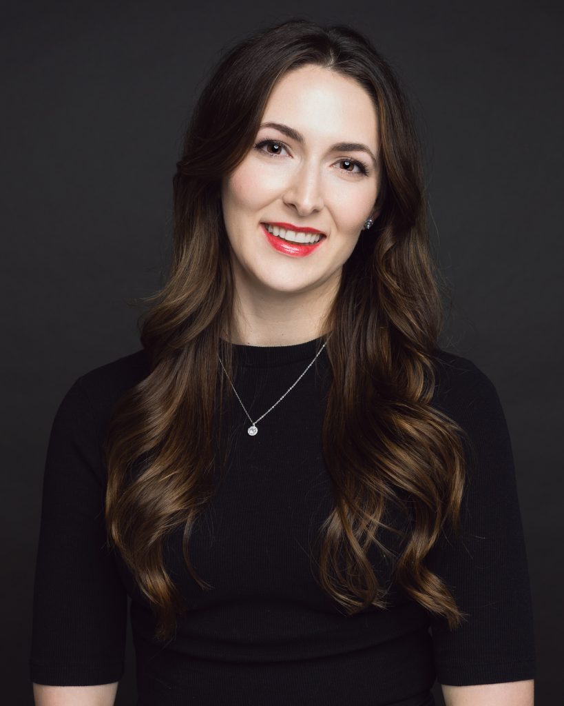Classic business headshot of a woman against a dark studio background