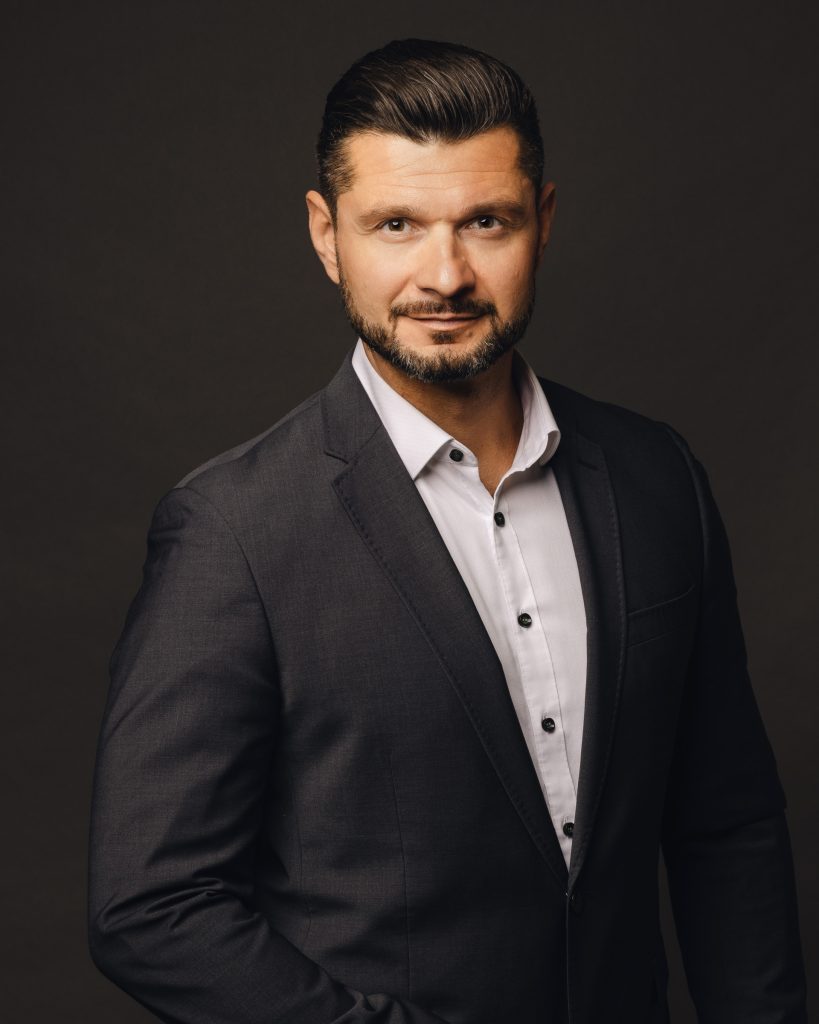 Executive business headshot of a man against a dark studio background