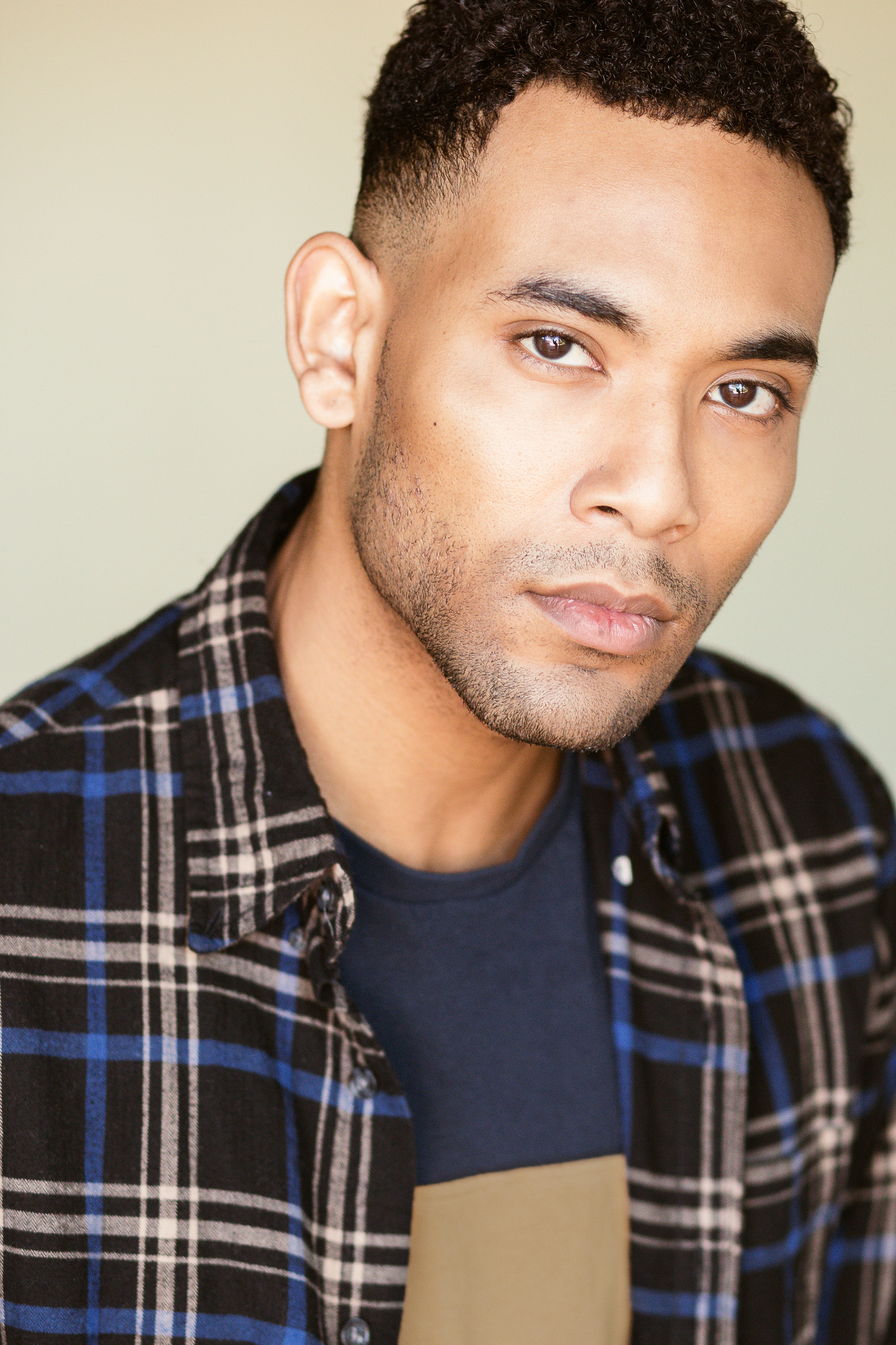 Male actor headshot in a plaid shirt with a relaxed expression