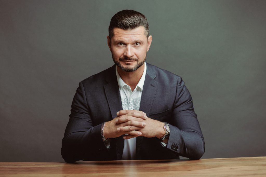 Professional business portrait of a man in a suit seated at a table