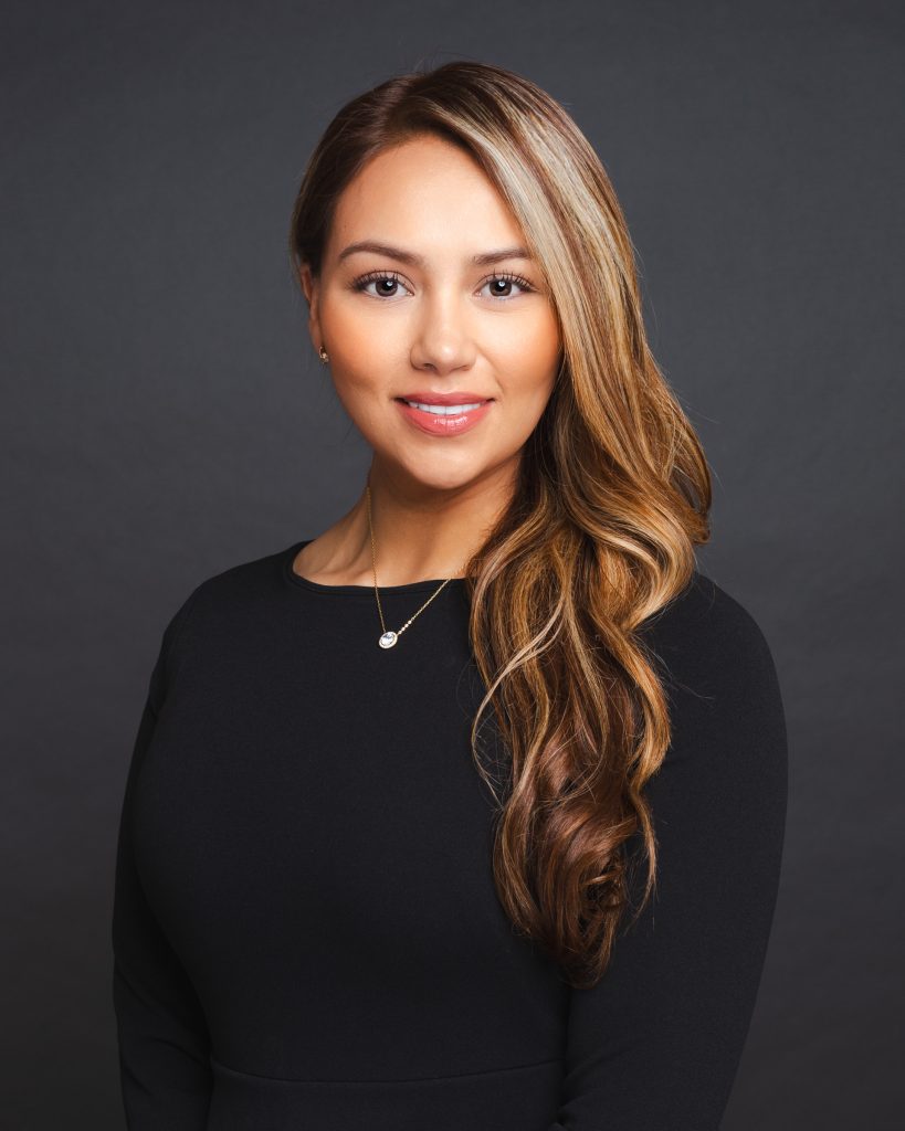 Professional business headshot of a woman against a dark gray background