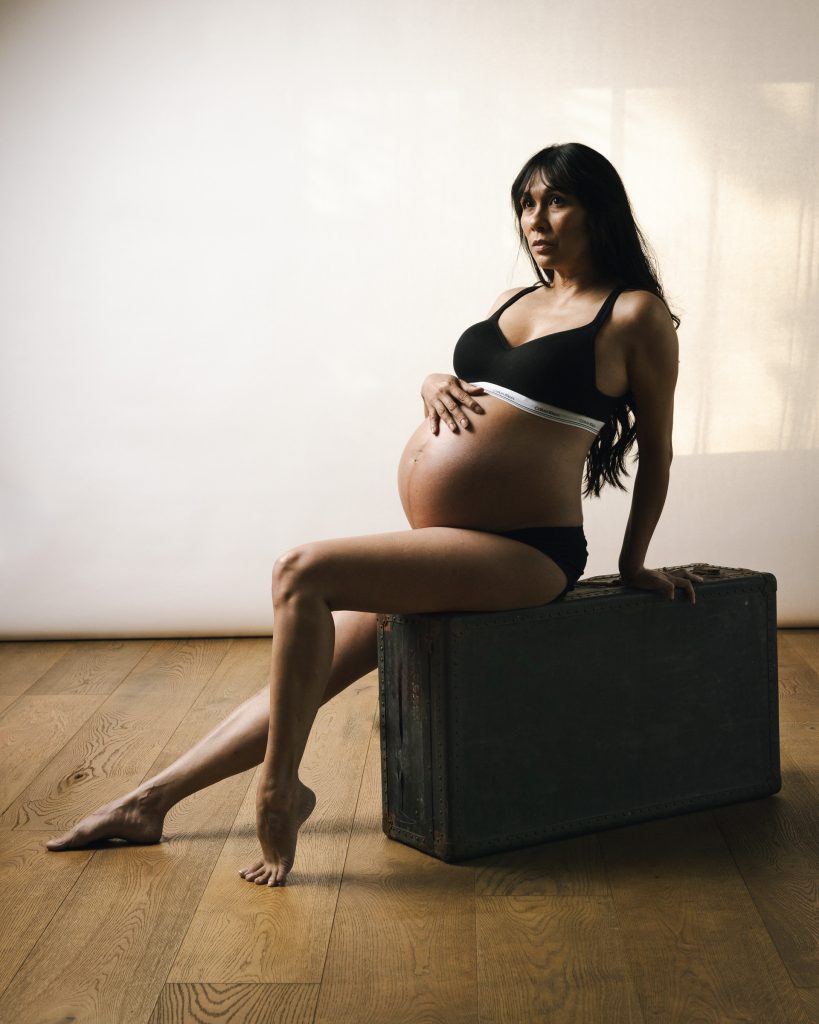 Pregnant woman seated in a studio for a maternity portrait