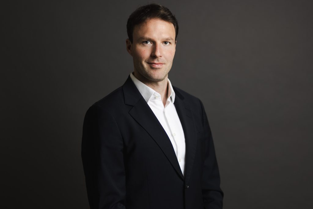 Classic studio headshot of a man in a black suit jacket and white shirt