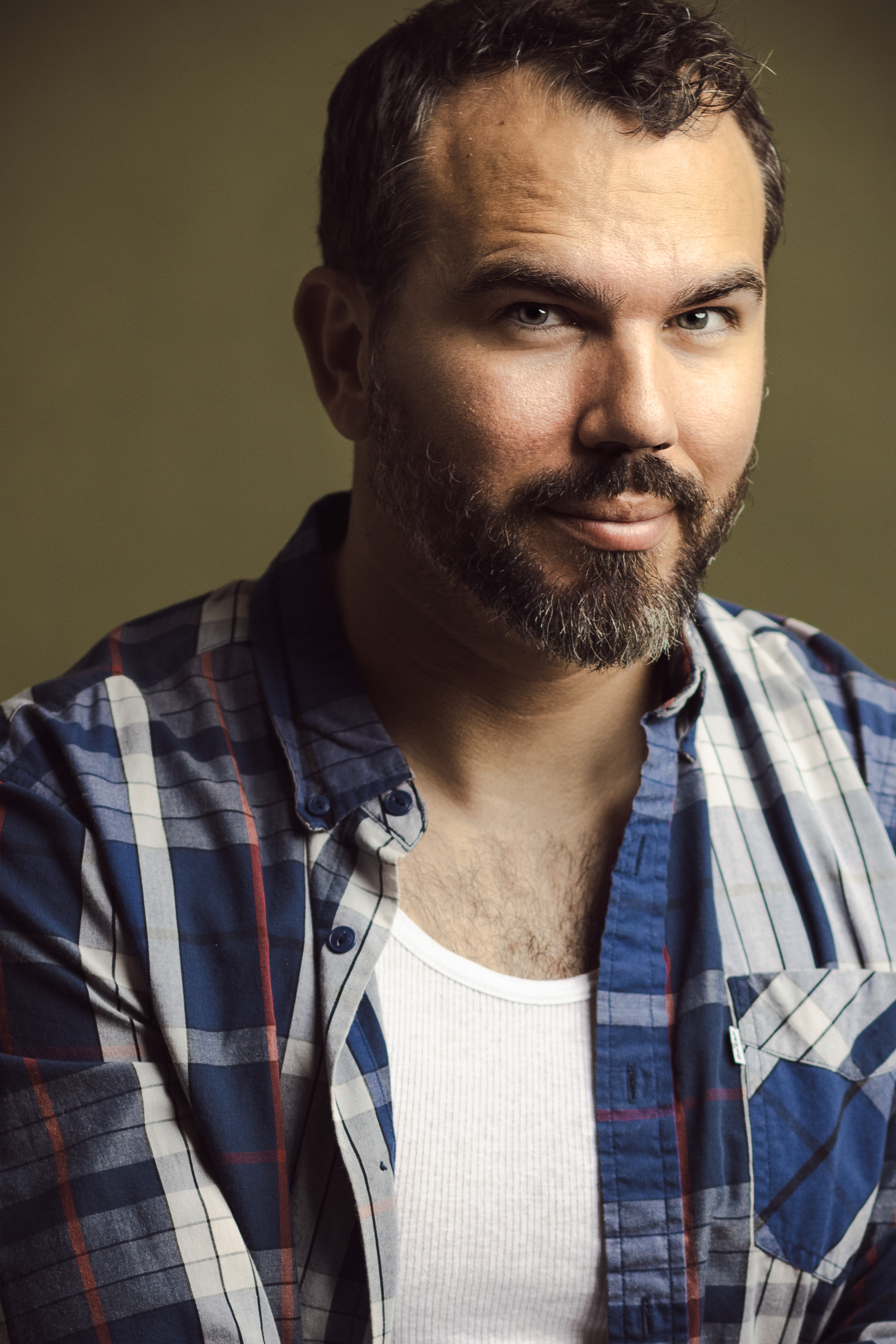 Theatrical headshot of a bearded male actor with dramatic lighting